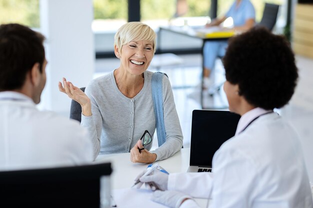 Mujer madura feliz hablando con su médico en la clínica médica