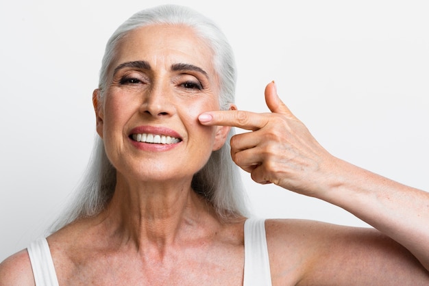 Mujer madura feliz que aplica la crema