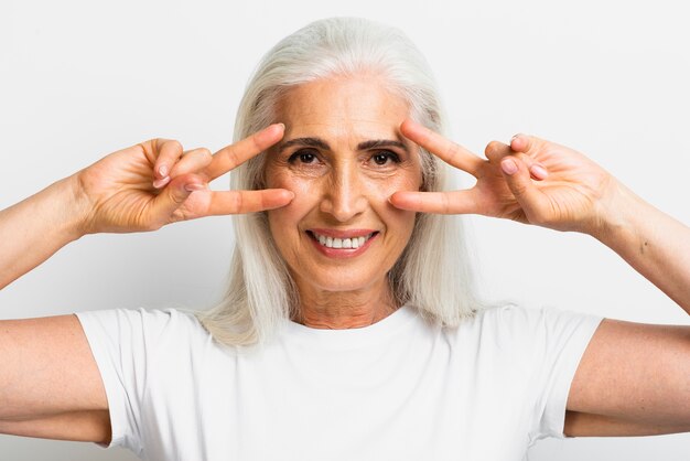 Mujer madura feliz que muestra el signo de la paz