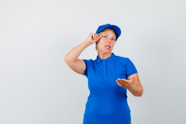 Mujer madura fingiendo hacer maquillaje en camiseta azul