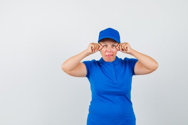 Mujer madura fingiendo hacer maquillaje en camiseta azul