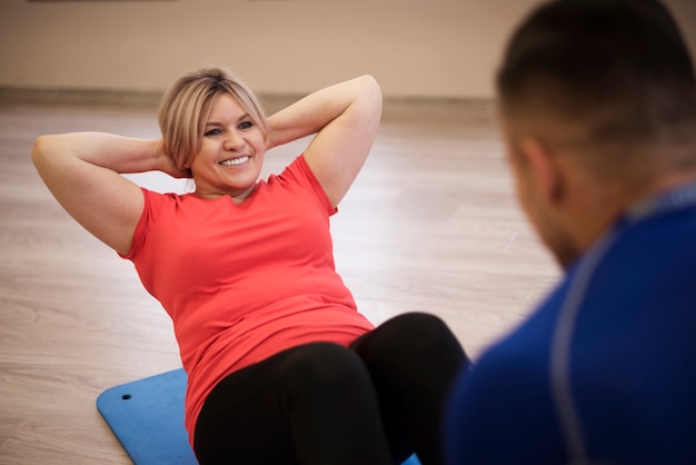 Mujer madura haciendo ejercicio con entrenador