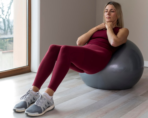 Mujer madura en interiores con pelota de fitness