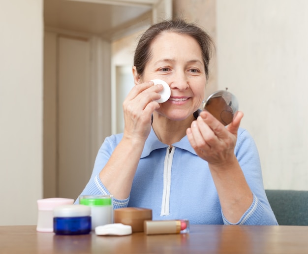 Mujer madura limpia el maquillaje