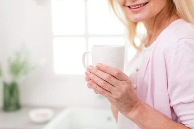 Foto gratuita mujer madura linda del primer que sostiene una taza