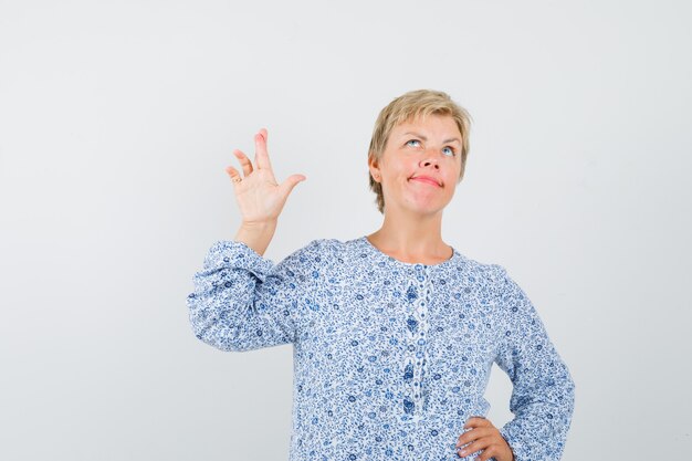 Mujer madura, manteniendo los dedos cruzados en camisa y mirando vacilante