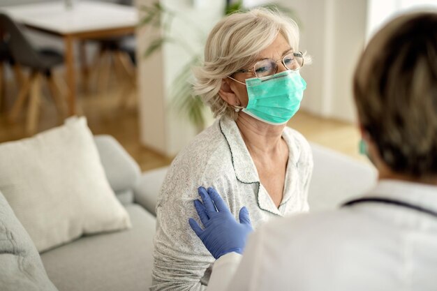 Mujer madura con mascarilla protectora comunicándose con su médico en casa