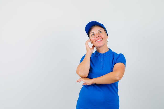 Mujer madura mirando hacia arriba en camiseta azul y mirando pensativo