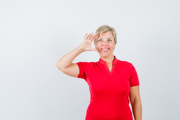 Mujer madura mirando lejos en camiseta roja y mirando esperanzado