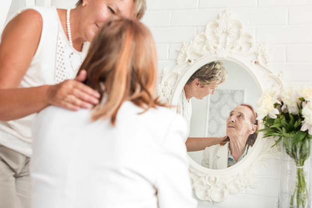 Foto gratuita mujer madura mirando a su madre sentada frente al espejo