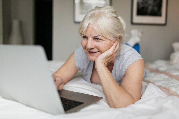 Mujer madura, navegación, computadora portátil, en, dormitorio