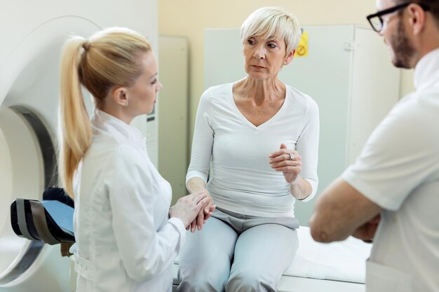 Mujer madura preocupada que se somete a un examen de resonancia magnética y se comunica con los médicos antes del procedimiento en el hospital