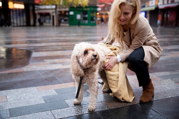 Mujer madura secando a su perro durante su paseo mientras llueve