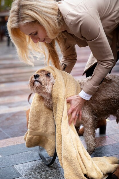 Mujer madura secando a su perro durante su paseo mientras llueve