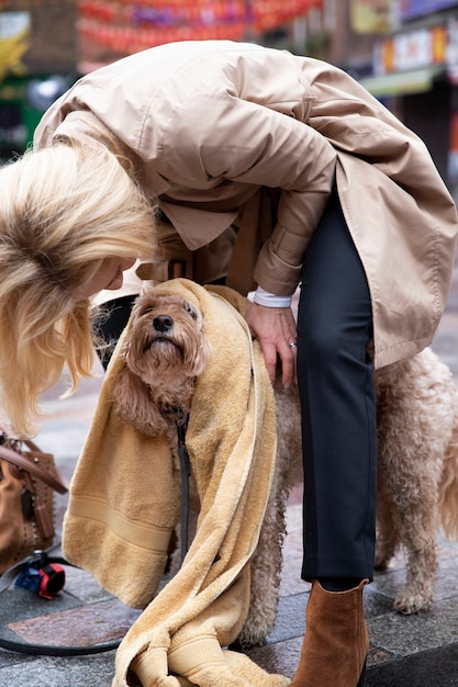 Mujer madura secando a su perro durante su paseo mientras llueve