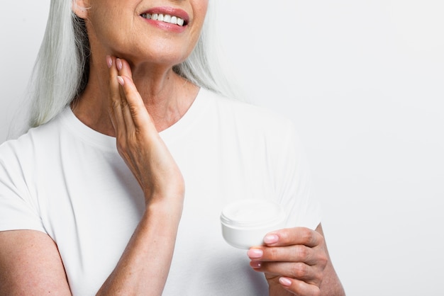 Foto gratuita mujer madura sonriente que aplica el tratamiento