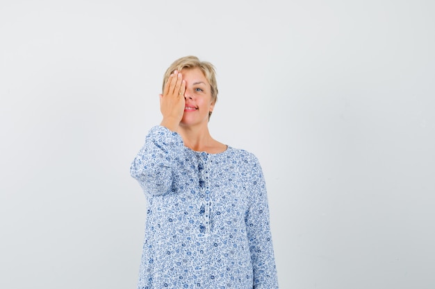 Mujer madura en vestido cubriendo un ojo con la mano