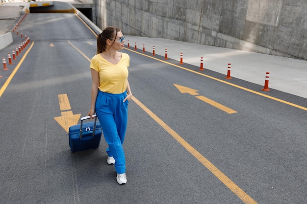 mujer con maleta moviéndose en la carretera