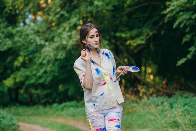 Mujer manchada de pintura caminando por un bosque