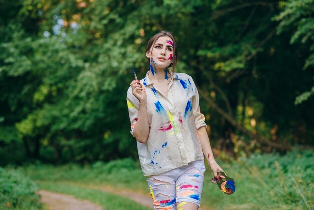 Mujer manchada de pintura caminando por un campo con árboles