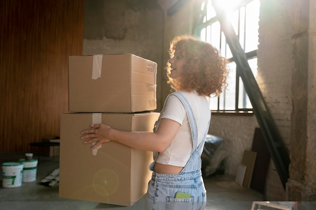 Foto gratuita mujer manejando pertenencias en cajas de cartón para mudarse a casa nueva