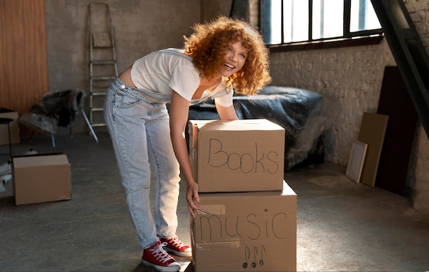 Foto gratuita mujer manejando pertenencias en cajas de cartón para mudarse a casa nueva