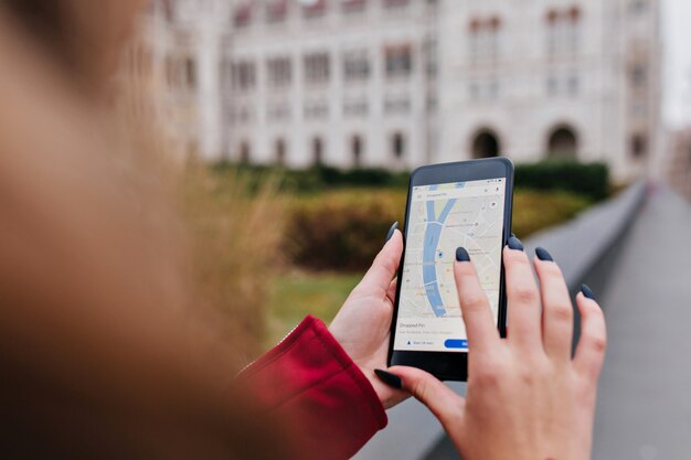 Mujer con manicura de moda con gps para buscar de manera correcta