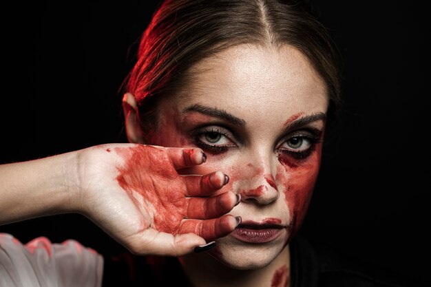 Mujer con mano ensangrentada y maquillaje