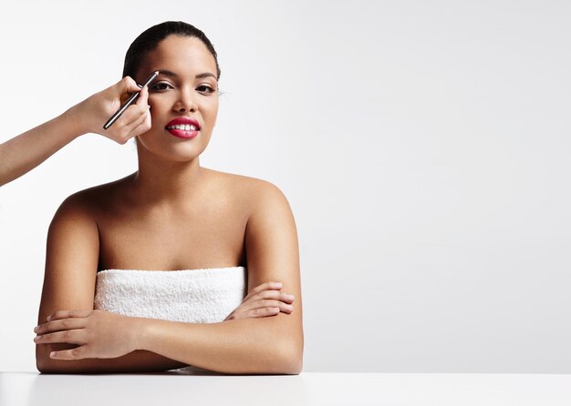 Mujer y mano haciendo un maquillaje de cejas