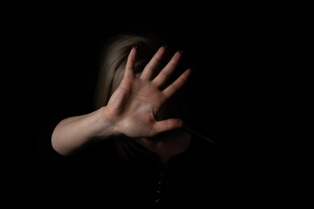Mujer con la mano levantada sobre fondo negro. aislado sobre fondo negro