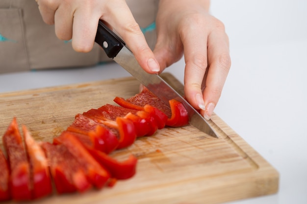 Mujer manos cortar pimiento a bordo