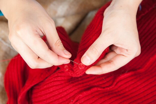 Mujer manos cosiendo un botón