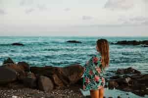 Foto gratuita mujer en manta de pie en la orilla del mar