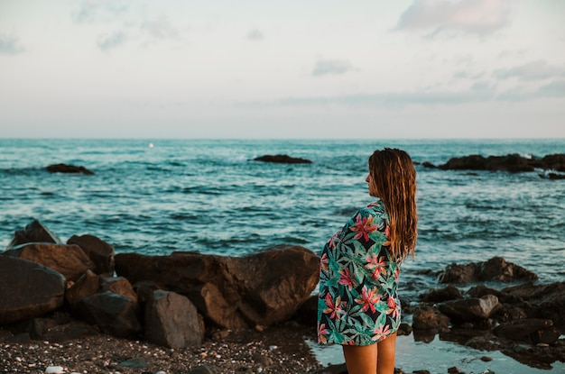 Mujer en manta de pie en la orilla del mar