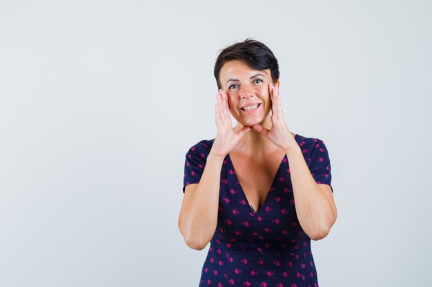 Mujer manteniendo las manos para decir el secreto en el vestido y mirando feliz