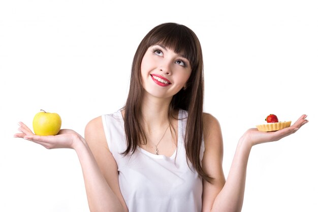 Mujer con una manzana en una mano y un pastel en la otra