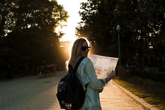 Mujer con mapa en el parque en la puesta de sol