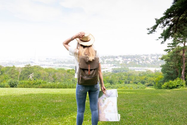 Mujer con mapa sostiene su sombrero