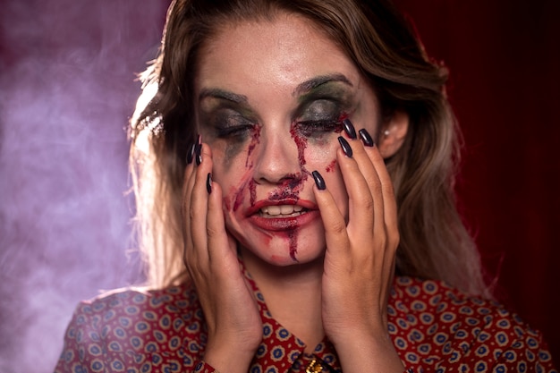 Foto gratuita mujer con maquillaje como sangre sosteniendo su cabeza