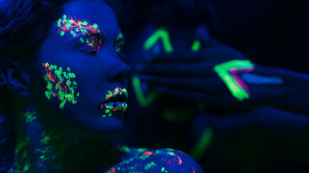Mujer con maquillaje fluorescente en cara y mano