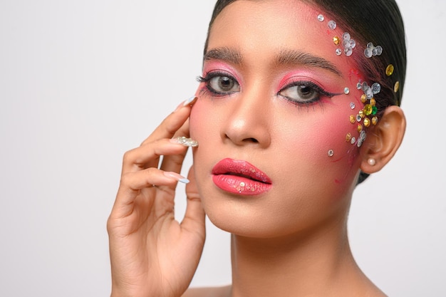 Mujer con maquillaje rosa y adornos en su rostro aislado en blanco