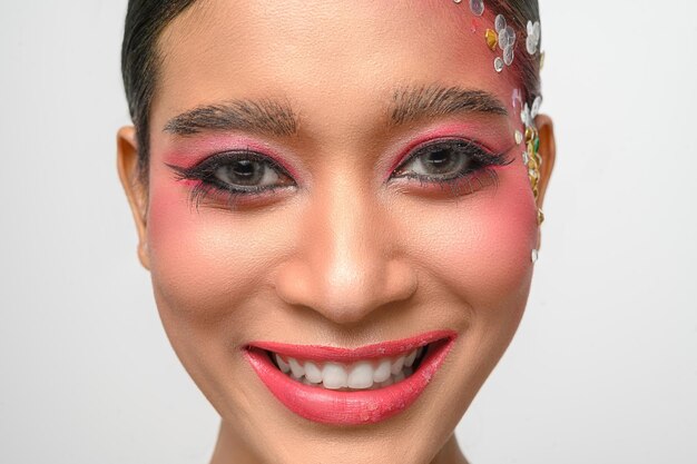 Mujer con maquillaje rosa y adornos en su rostro aislado en blanco