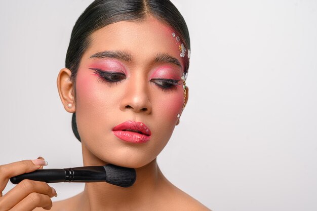 Mujer con maquillaje rosa y sosteniendo un pincel de rubor aislado en blanco