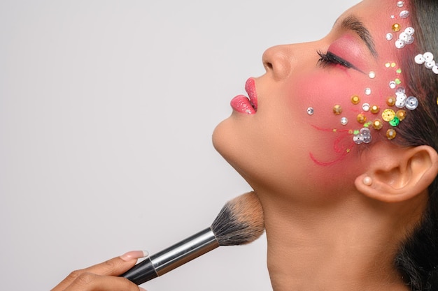 Mujer con maquillaje rosa y sosteniendo un pincel de rubor aislado en blanco