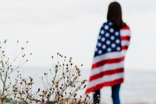 Mujer por el mar cubierta en bandera americana