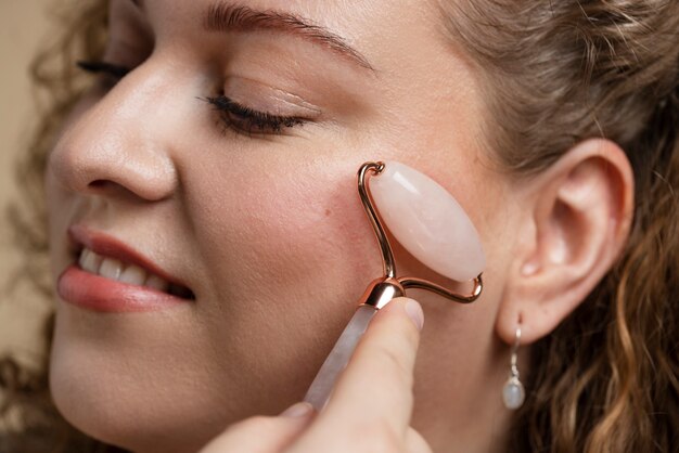 Mujer masajeando la cara con gua sha de cerca