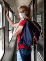 Foto gratuita mujer con máscara y auriculares en tren