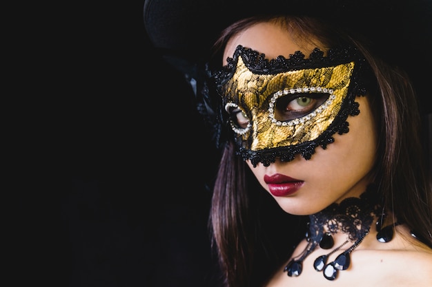 Foto gratuita mujer con una máscara de carnaval en un fondo oscuro