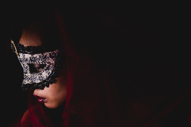 Mujer con una máscara de carnaval en un fondo oscuro