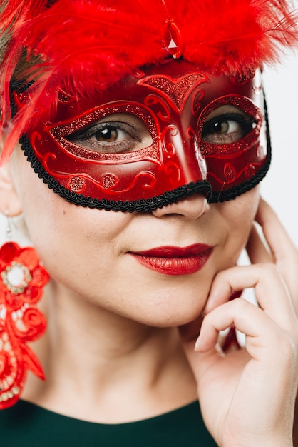 Mujer en máscara de carnaval rojo con pluma